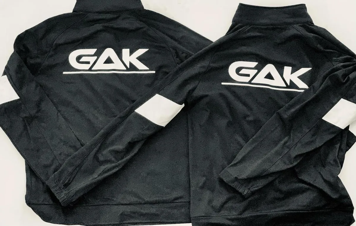 Two black GAK track jackets with white logo across the back